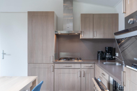 Moderne Küche mit Holzschränken, Gasherd und Kaffeemaschine im Pavilion bei Kagerplassen, Niederlande.