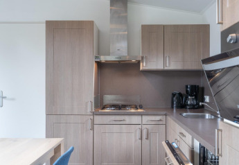 Moderne Küche mit Holzschränken, Gasherd und Kaffeemaschine im Pavilion bei Kagerplassen, Niederlande.