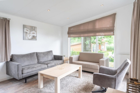 Helles und modernes Wohnzimmer mit großen Fenstern und grauen Möbeln im Pavilion bei Kagerplassen, Niederlande.