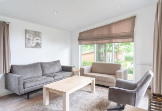 Heldere, moderne woonkamer met grote ramen en grijze zetels in Pavilion aan Kagerplassen, Nederland.