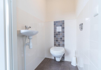 Moderne toilet med væghængt toilet og lille håndvask på Pavilion at Kagerplassen, Holland.