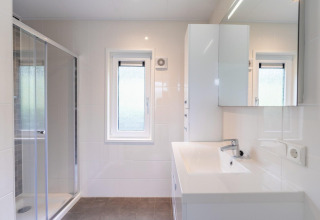 Salle de bains moderne au Pavilion at Kagerplassen, Pays-Bas, avec douche, fenêtre et décoration blanche.