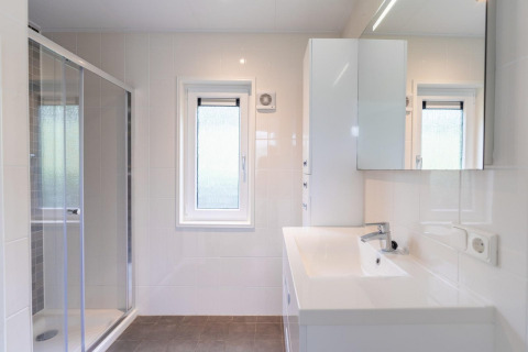 Modernes Badezimmer im Pavilion at Kagerplassen in den Niederlanden mit Dusche, Fenster und weißen Fliesen.