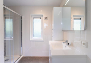 Baño moderno en el Pavilion at Kagerplassen en los Países Bajos con ducha, ventana y decoración blanca.