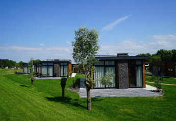 Moderne pavillon-lodges ved Kagerplassen i Holland omgivet af grønt græs og klar blå himmel.