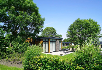 Moderno padiglione lodge al Kagerplassen nei Paesi Bassi circondato da alberi, giardino e terrazza esterna.