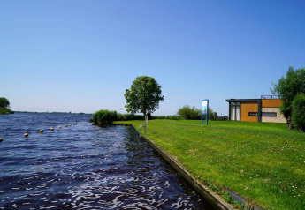 Foto del Pavilion presso Kagerplassen nei Paesi Bassi, con prato, acqua, albero e lodge moderno.
