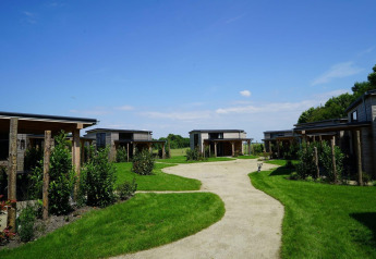 Casas pequeñas de madera en Kagerplassen, Países Bajos, rodeadas de césped verde y cielo azul.
