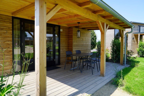 Terrasse en bois d'une Tiny House à Kagerplassen, Pays-Bas, avec table, chaises et vue sur le jardin.