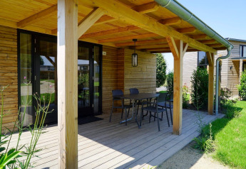 Træveranda ved et Tiny House ved Kagerplassen i Holland med havemøbler og udsigt til grønne omgivelser.