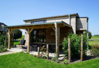 Tiny House aux Kagerplassen aux Pays-Bas, extérieure en bois, terrasse couverte et jardin verdoyant.