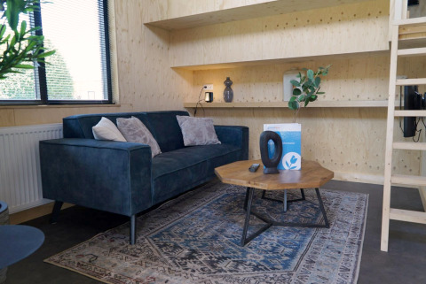 Salon moderne et lumineux dans un Tiny House à Kagerplassen, Pays-Bas, avec canapé bleu et table bois.