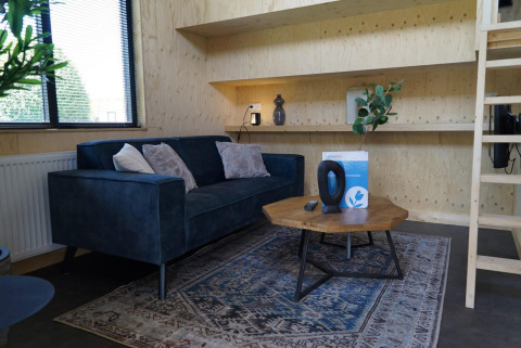 Lyst og moderne stue i Tiny House ved Kagerplassen, Holland, med blå sofa og træmøbler.