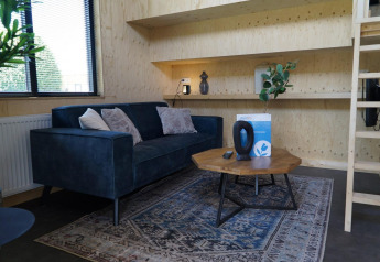 Sala moderna y acogedora del Tiny House en Kagerplassen, Países Bajos, con sofá azul y mesa de madera.