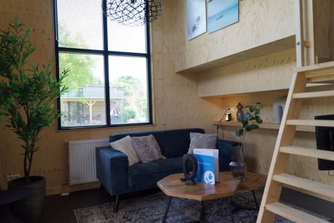 Moderne woonkamer in Tiny House aan Kagerplassen, Nederland, met blauwe zetel en houten wanden.