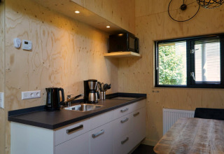 Cuisine de tiny house moderne à Kagerplassen, Pays-Bas, avec mur en bois et équipements de base.