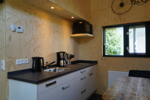 Moderna cucina di tiny house a Kagerplassen, Paesi Bassi, con pareti in legno e macchina del caffè.