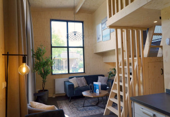 Indvendigt billede af Tiny House ved Kagerplassen i Holland med trappe, sofa og store vinduer.