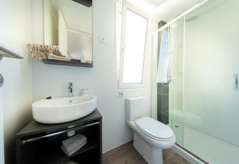 Modern lodge bathroom featuring a sink, toilet, mirror, large window, glass shower and storage shelves.