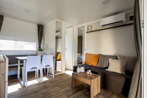 Moderne lodge met zithoek, eettafel, houtenvloer, airco en warme, gezellige inrichting.