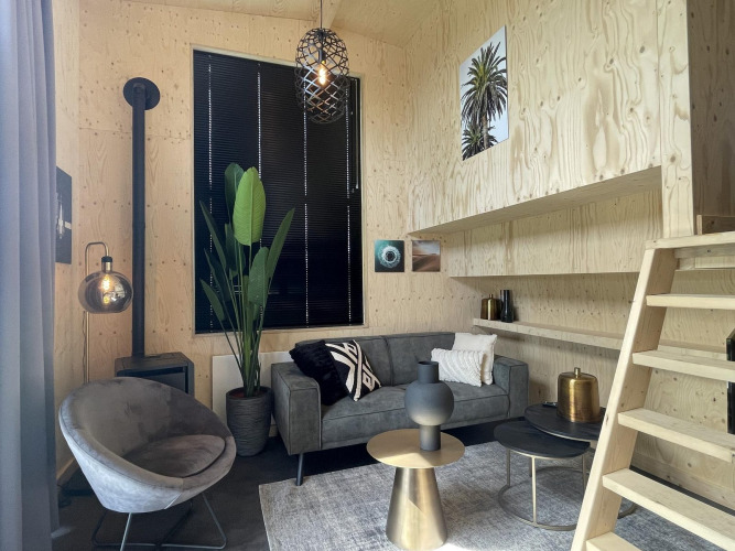 Modern cozy living area at Tiny House Plus in De Rijp, Netherlands, featuring stylish furniture and wood walls.