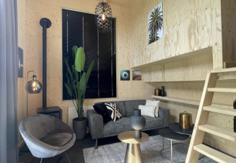 Moderne, knusse woonkamer in Tiny House Plus te De Rijp, Nederland, met stijlvolle meubels en houten wanden.