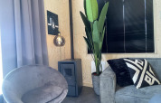 Sala moderna en Tiny House Plus, De Rijp, Países Bajos, con muebles grises y una planta grande.