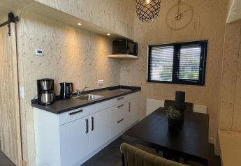 Moderne køkken og spiseområde i Tiny House Plus-lodgen ved De Rijp, Holland, med trævægge og sort interiør.