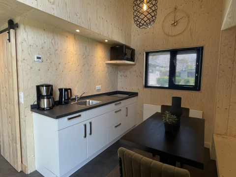 Moderne keuken en eetgedeelte in Tiny House Plus lodge te De Rijp, Nederland, met houten wanden.
