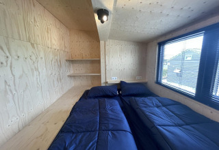 Slaapkamer in Tiny House Plus in De Rijp, Nederland, met tweepersoonsbedden en blauw beddengoed in houtlook.