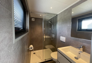 Modern badkamer bij Tiny House Plus, De Rijp, Nederland, met douche, toilet en wastafelmeubel.