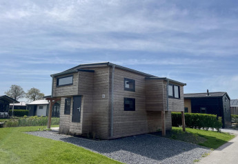 Moderne træhytte kaldet Tiny House Plus ved De Rijp, Holland, under en klar blå himmel med grønt græs.