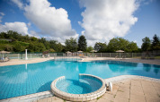 Swimmingpool med liggestole og parasoller på Huttopia Royat feriepark i Auvergne-Rhône-Alpes, Frankrig.