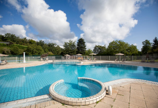 Swimmingpool med liggestole og parasoller på Huttopia Royat feriepark i Auvergne-Rhône-Alpes, Frankrig.