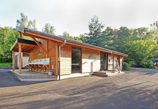 Wooden building with outdoor sink area at Huttopia Royat holiday park in Auvergne-Rhône-Alpes, France.