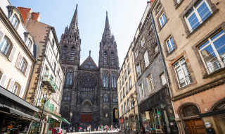 Vista callejera cerca de Royat, Auvergne-Rhône-Alpes, Francia, con una catedral gótica y edificios históricos.
