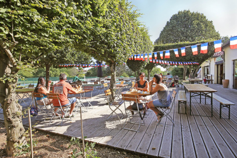 Terraza al aire libre en Huttopia Royat, parque vacacional en Auvergne-Rhône-Alpes, Francia, con banderines.