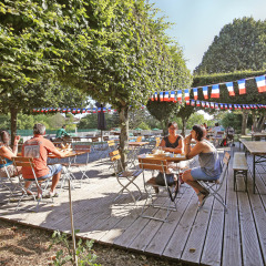 Terraza al aire libre en Huttopia Royat, parque vacacional en Auvergne-Rhône-Alpes, Francia, con banderines.