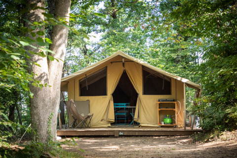 Gran tienda de lona sobre plataforma de madera en el bosque en Huttopia Royat, Auvergne-Rhône-Alpes, Francia.