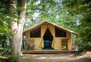 Et stort lærredstelt på en træplatform i en skov ved Huttopia Royat, Auvergne-Rhône-Alpes, Frankrig.