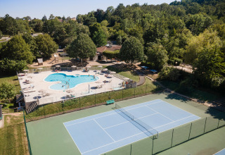 Vista aérea del parque vacacional Huttopia Royat en Auvergne-Rhône-Alpes, Francia, con piscina y cancha de tenis.