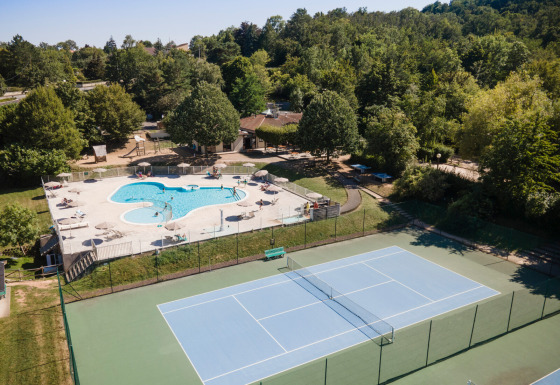 Aerial view of Huttopia Royat holiday park in Auvergne-Rhône-Alpes, France, featuring pool and tennis court.
