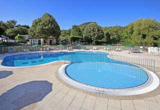 Outdoor swimming pool at Huttopia Royat holiday park in Auvergne-Rhône-Alpes, France, surrounded by trees.
