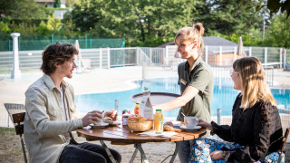 Una pareja disfruta de un desayuno al aire libre junto a la piscina en Huttopia Royat, Auvergne-Rhône-Alpes, Francia.