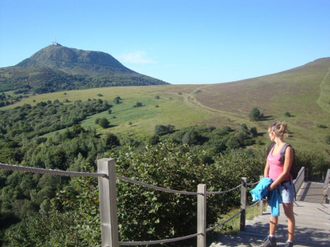 Woman hiker enjoying the scenic green hills near Royat in Auvergne-Rhône-Alpes, France, on a sunny day.