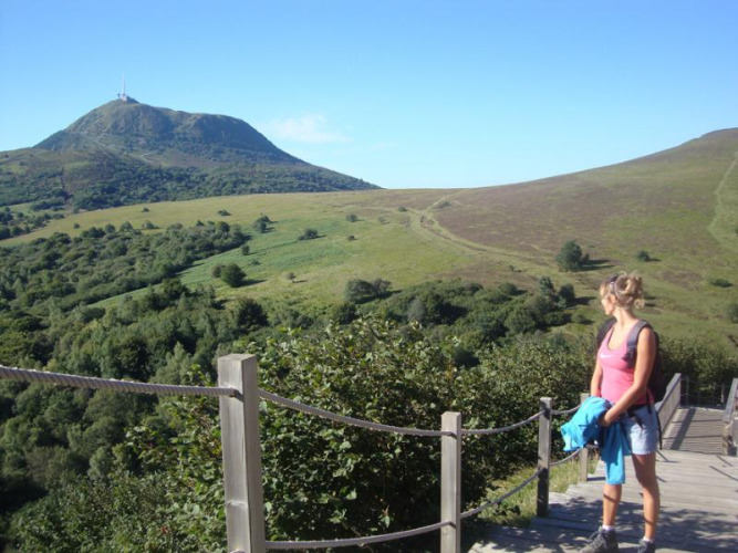 Frau wandert und genießt den Blick auf grüne Hügel in der Nähe von Royat, Auvergne-Rhône-Alpes, Frankreich.