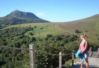 Woman hiker enjoying the scenic green hills near Royat in Auvergne-Rhône-Alpes, France, on a sunny day.