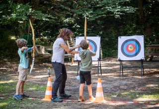 Kinderen leren boogschieten met begeleider in de natuur op vakantiepark Huttopia Royat in Auvergne-Rhône-Alpes, Frankrijk.