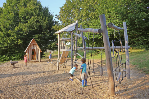 Kinderen spelen op een houten speeltuin in de natuur, Huttopia Royat vakantiepark, Frankrijk.