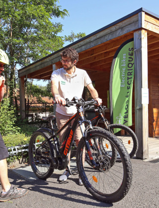 Dos hombres con bicicletas frente a una cabaña en Huttopia Royat, parque vacacional en Auvernia-Ródano-Alpes.